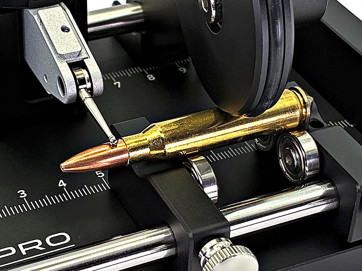 black4st® CG-PRO, Detail: die Patrone liegt mit dem Hülsenkörper auf den Auflagerollen, das Antriebsrad liegt oben an; die Messuhr tastet am Geschoss an, Hals und Geschoss bleiben frei