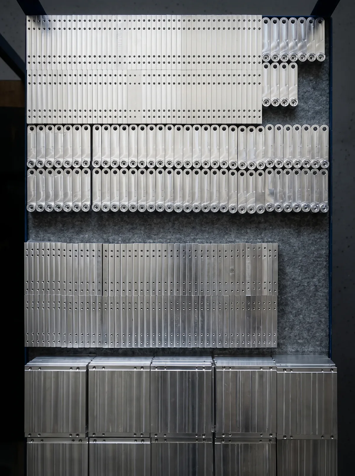 Aus dem Vollen gefräste black4st®-Bauteile aus Aluminium EN AW-6061, blank vor dem Eloxieren, in Reihen aufgereiht